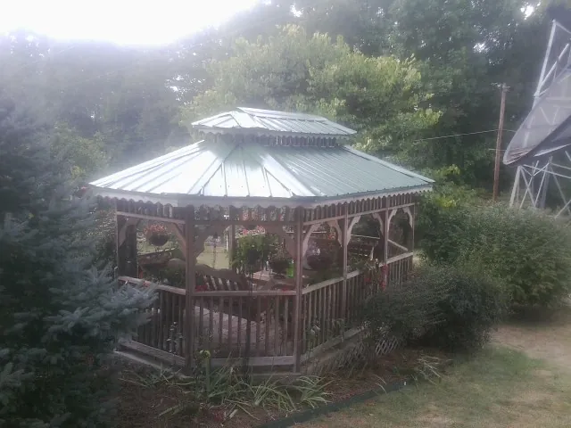 Green metal roof on a backyard gazebo surrounded by garden beds in Lyndon