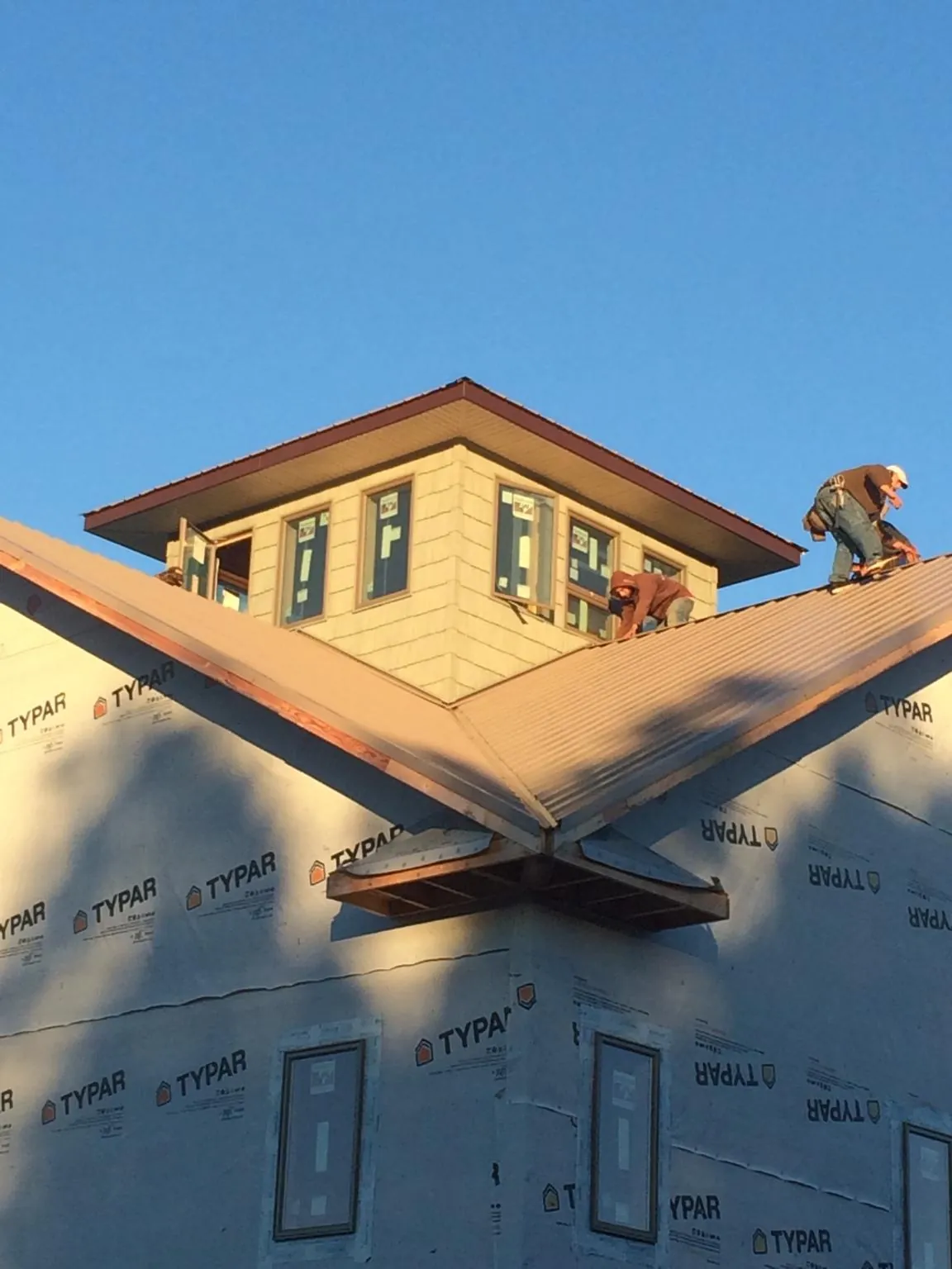 Roofers working around a rooftop cupola on a new metal roof at sunset — Roof Waterproofing in Lyndon by Roofing Brothers